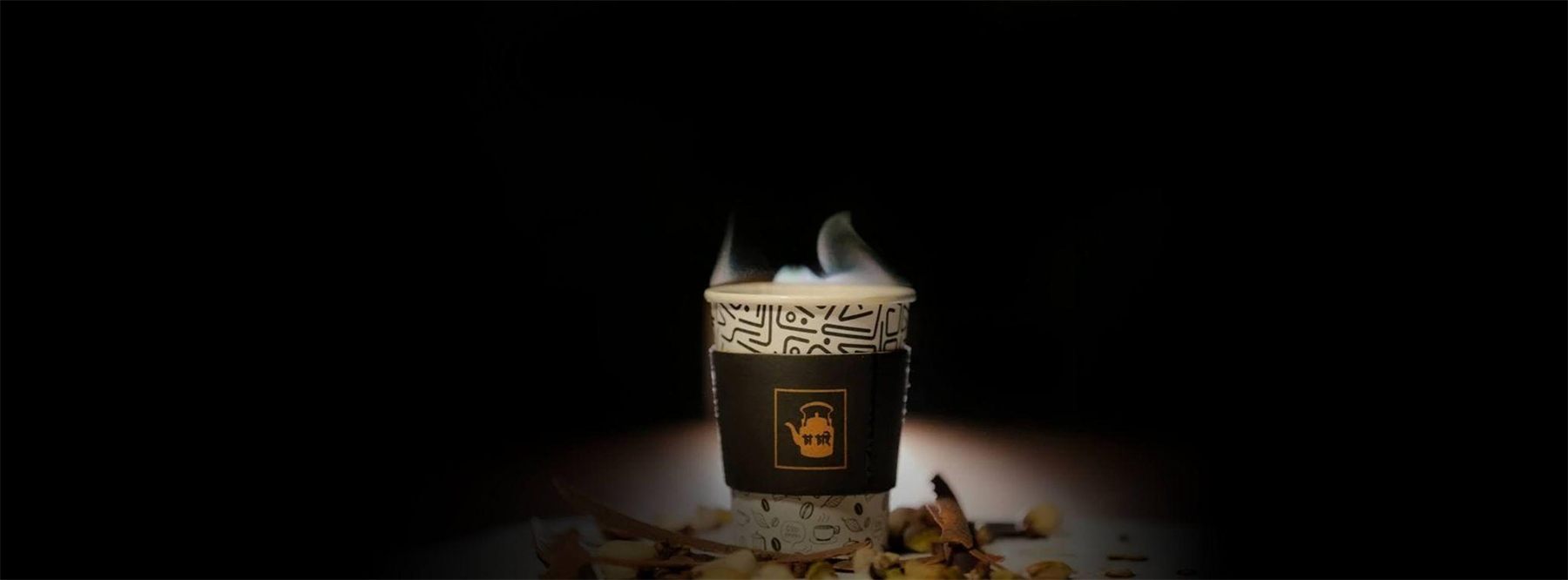 A steaming Cha Chai cup lit against a dark background